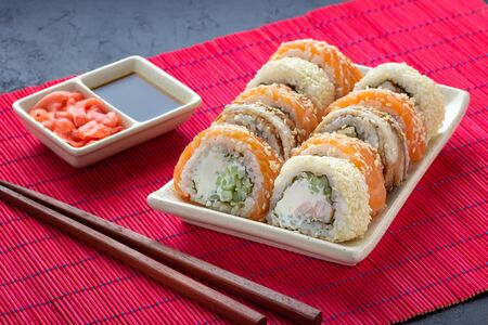 Sushi roll, chopsticks, soy sauce, ginger and red bamboo mat.の写真素材