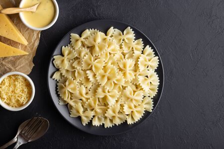 Tasty appetizing cooked italian farfalle pasta (bow-tie or butterfly) in a plate. Above view with copy space. Black background.の写真素材