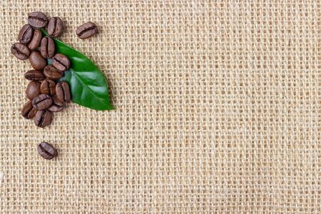Coffee beans and leaf over burlap background. Top view with copy space.の写真素材