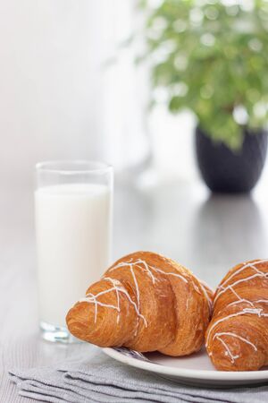 Breakfast. A glass of milk and two croissants.の写真素材