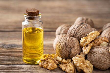 Glass bottle with walnut oil and walnut kernel on a wooden table. Cosmetic and therapeutic product.の写真素材