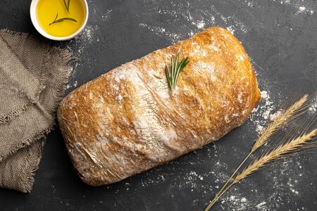 Crispy italian ciabatta bread on black background. Top view, flat lay.