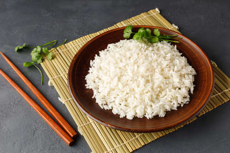 Boiled rice, chopsticks and bamboo napkin on a gray concrete background. Asian food.の写真素材