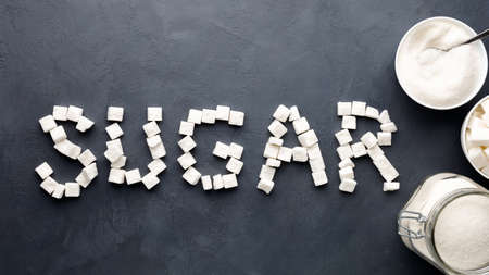 Top view on black background with sugar cubes in the form of text "sugar".の写真素材