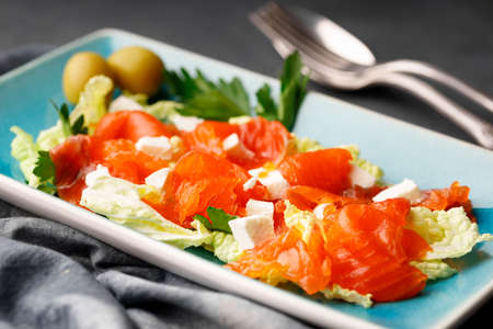 Gourmet food - salad from red raw salmon and herbs on a rectangular plate. close-up.の写真素材