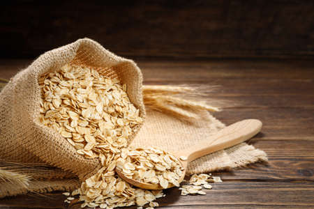 Oatmeal in a bag and oat flakes on a wooden table.の写真素材