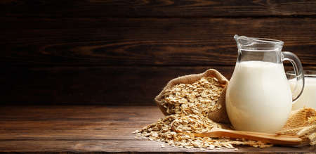 Oat flakes, jug and glass of milk on a wooden background. Copy space for text.の写真素材