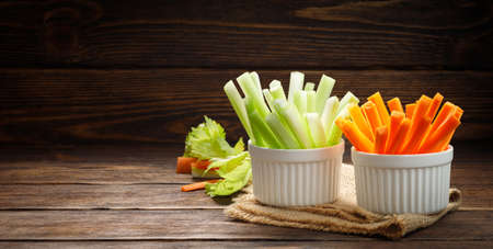 Fresh vegetables - chopped celery sticks and carrots on a wooden background. Diet and healthy food. Copy space for text.の写真素材