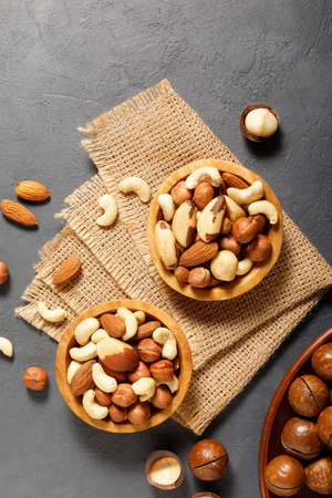 Various nuts in bowl - cashew, hazelnuts, almonds, brazilian nuts and macadamia on a gray stone...