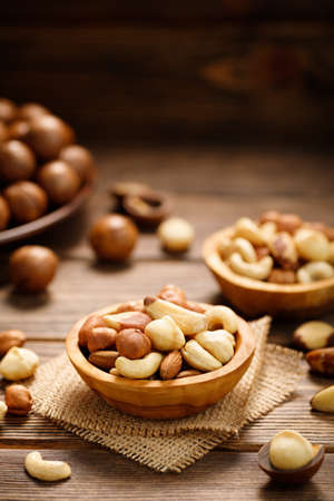 Various nuts in bowl - cashew, hazelnuts, almonds, brazilian nuts and macadamia on a wooden table....