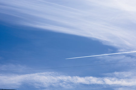 Airplane trail in the blue sky with white clouds and copy spaceの写真素材