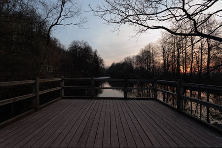 Wooden bridge over the river at sunset with trees in the backgroundの写真素材