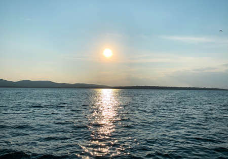 Beautiful sunset over coastline while sailing through the calm seaの写真素材