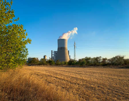 Cooling tower of thermal power plant behind plowed field in autumn duskの写真素材