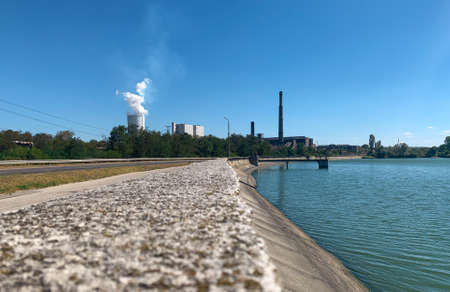 Thermal power plant dam wall with coal facilities and steaming cooling tower at distant backgroundの写真素材
