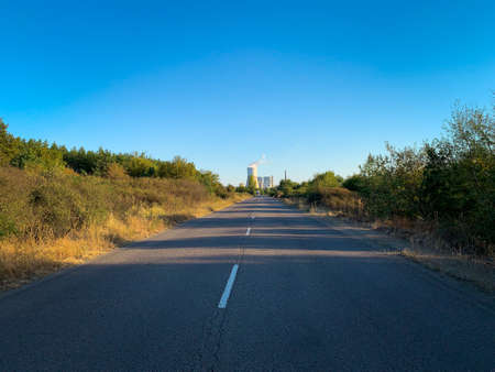 Empty road at sunset with thermal power plant in distant on backgroundの写真素材