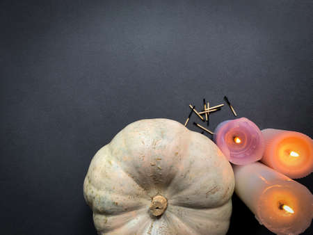 Top view decoration of pumpkin and glowing candles with burnt matches next to it on a dark background with a copy spaceの写真素材