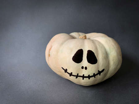 Halloween jack o lantern painted face white pumpkin on dark gray background with copy spaceの写真素材