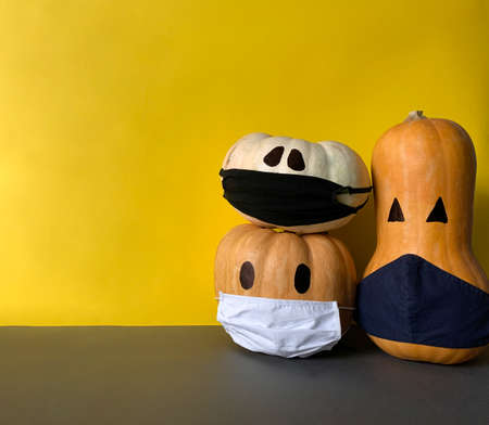 Halloween and covid-19 concept. Halloween pumpkins with protective mask against Coronavirus on yellow backgroundの写真素材