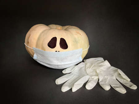 Safe Halloween 2020 during the Coronavirus pandemic. Halloween pumpkin with face mask and glovesの写真素材