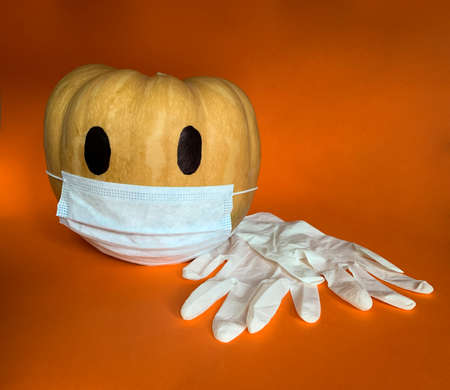 Halloween pumpkin in COVID-19 pandemic wearing protective mask and medical gloves next to itの写真素材