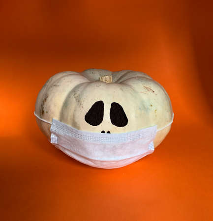 New normal concept. Halloween pumpkin in a protective medical mask on a orange background with copy spaceの写真素材