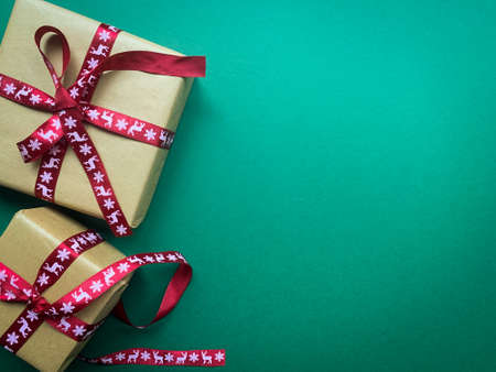 Christmas gifts with red ribbons on green background. Copy space Flat lay creative design.の写真素材