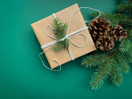 Handcraft Christmas present wrapped in craft paper. Flat lay green background with fir branches with copy space.の写真素材