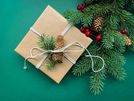 Top view of handmade Holiday, Christmas or New Year present wrapped in paper and decorated with   spruce branches on a green background.の写真素材