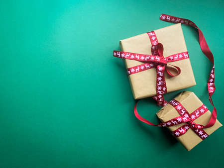 Christmas gift boxes warped in craft paper and tied with a red ribbons. Minimal Christmas, Holiday green background, banner, header, poster. Flat lay. Copy space.の写真素材