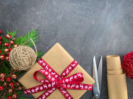 Preparing Christmas gifts background. Dark wooden background workspace with with craft paper, scissors and winter decoration. Top view, copy space.の写真素材