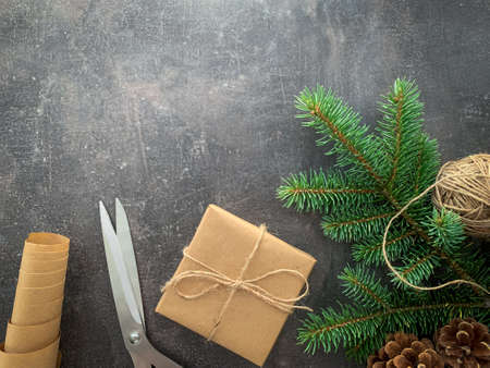 Vintage gift box on wooden table. Gift wrapping. Craft paper roll, ball of twine, spruce with pine cones and scissors. Top view with copy space Christmas background.の写真素材