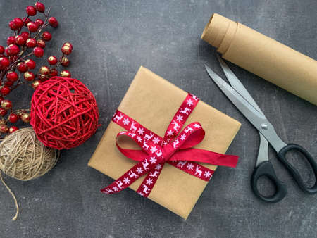 Christmas workshop. Present, Craft paper roll, scissors, twine, red berries and christmas decoration on wooden table.の写真素材
