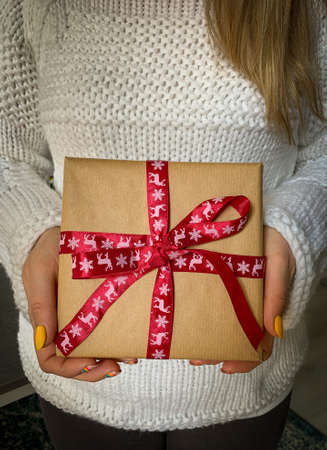 Woman in white sweater holds Christmas gift box with red ribbon.の写真素材