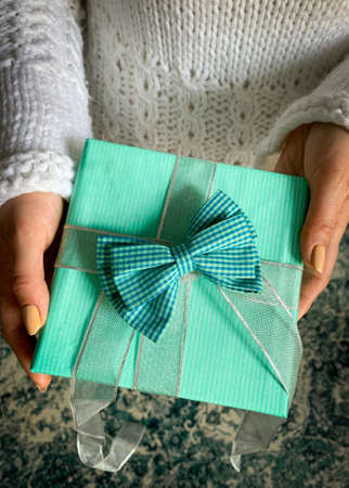 Woman wearing white sweater  giving a blue present.の写真素材