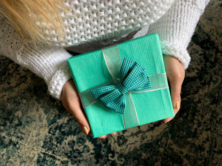 Woman giving surprise gift. Overhead view of hands holding present wrapped in blue paper.の写真素材