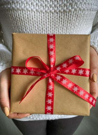 Woman in white sweater holds Christmas gift box with red ribbon.の写真素材