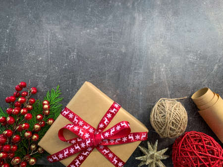 Gift box with red ribbon with Christmas decorations and fir tree branches on grey wooden table.の写真素材
