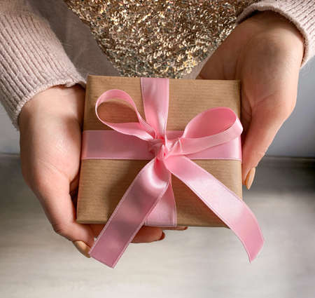 Gift box in hands. Present with pink bow. Holiday giving.の写真素材