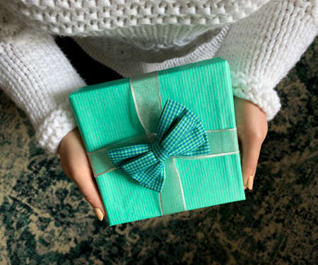 Woman wearing white sweater  giving a blue present.の写真素材