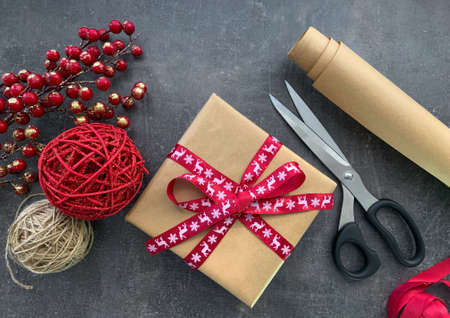 Preparing for Christmas. Present, wrapping paper, scissors and holiday decorations on dark wooden background.の写真素材