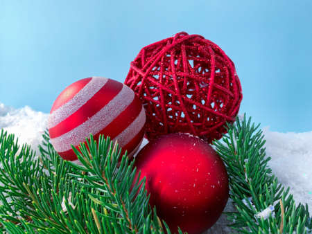 Close up red christmas balls on pine tree branches on snowy background.の写真素材