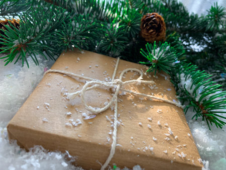 Hand crafted gift on white snow background with fir branches illuminated by sun lightの写真素材