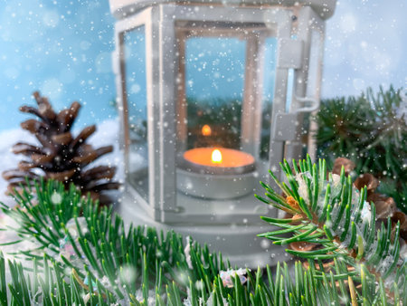 Blurred snowy Christmas background with candle light lantern, fir tree branches and pine cones on blue background.の写真素材