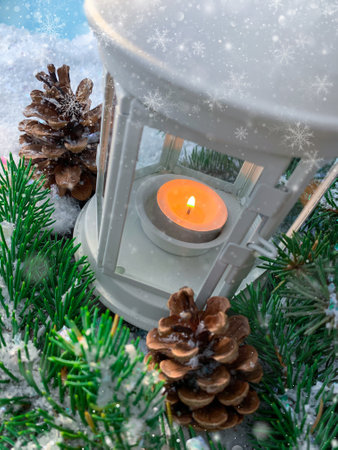 Abstract Merry Christmas holiday shiny composition. Burning candle lamp with pine tree on snowy blurred background.の写真素材
