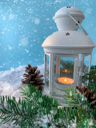 Abstract Merry Christmas holiday shiny composition. Burning candle lamp with pine tree on snowy blurred background.の写真素材