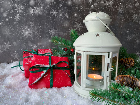 Holiday shiny christmas composition. Burning candle lamp with red gifts, pine cone, berries and fir tree. Christmas snow background with copy space.の写真素材
