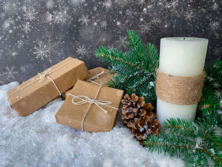 Snowfall over handmade candle and handcrafted Christmas gifts. Festive Holiday mood snowy glittering background.の写真素材