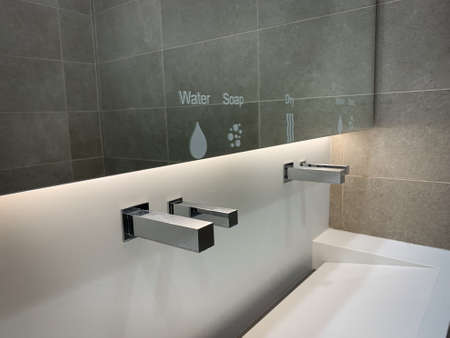 Modern white sink with big mirror and contemporary metal faucet with water, soap and dry symbols...