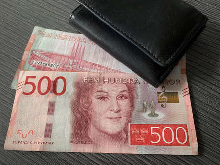 Sweden krone bills with black leather wallet isolated on dark wood background. Swedish krona money - 500 fem hundra kronor.の写真素材